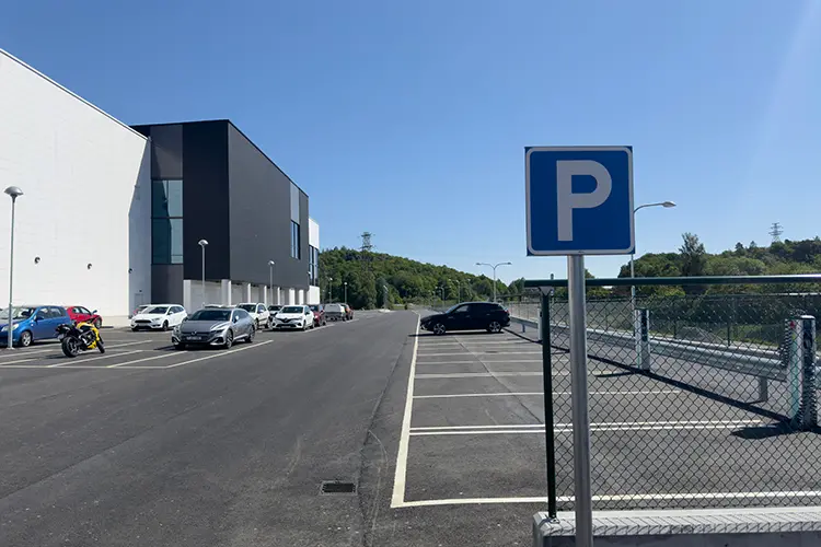 parkeringsskylt och parkeringsplatser intill en vit och svart byggnad 